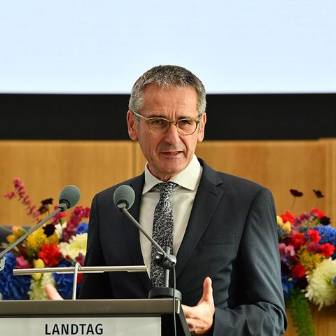 Hendrik Hering steht am Rednerpult im Plenarsaal. Im Hintergrund schmücken festliche Blumenbouquets den Tisch.