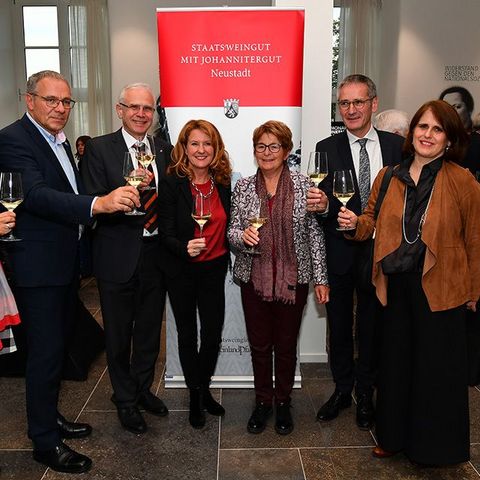 Gruppenbild im Foyer des Plenarsaals vor einem Aufsteller des Staatsweinguts mit Johannitergut Neustadt.