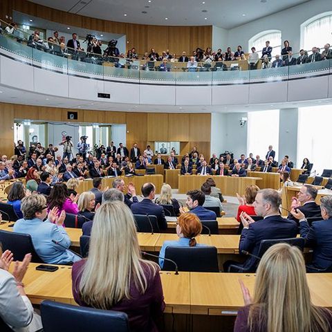 Die Abgeordneten sitzen applaudierend im Plenarsaal. Von der Besuchertribüne aus sehen zahlreiche Personen zu.