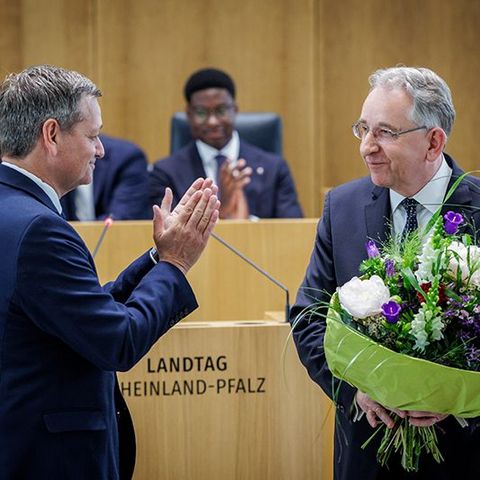 Herr Lammert steht mit einem großen Blumenstrauß im Plenarsaal. Vor ihm steht Christian Baldauf, der ihm applaudiert.