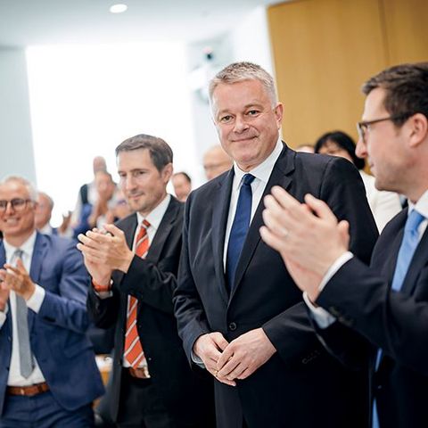 Ministerpräsident Gordon Schnieder steht inmitten applaudierender Abgeordneter.