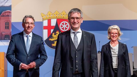 Die drei hochrangigen Politiker stehen vor dem Landeswappen des Landes Rheinland-Pfalz.