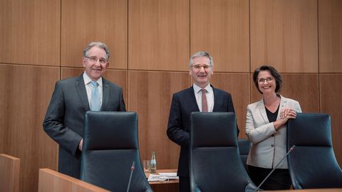 Die Mitglieder des Vorstands stehen lachend hinter den Sitzen des Sitzungsvorstands im Plenarsaal des Deutschhauses.