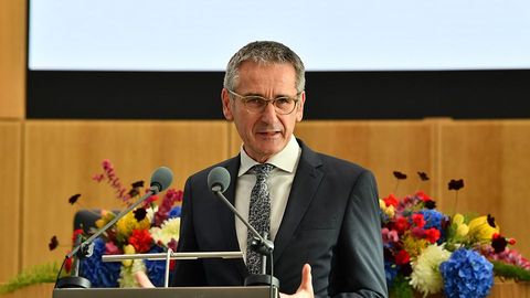 Hendrik Hering steht am Rednerpult im Plenarsaal. Im Hintergrund schmücken festliche Blumenbouquets den Tisch.