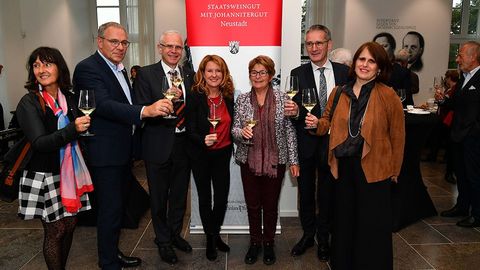 Gruppenbild im Foyer des Plenarsaals vor einem Aufsteller des Staatsweinguts mit Johannitergut Neustadt.