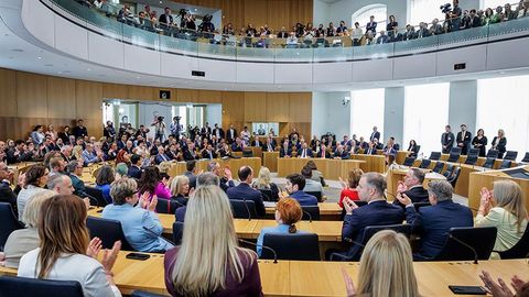 Die Abgeordneten sitzen applaudierend im Plenarsaal. Von der Besuchertribüne aus sehen zahlreiche Personen zu.