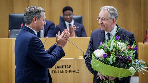Herr Lammert steht mit einem großen Blumenstrauß im Plenarsaal. Vor ihm steht Christian Baldauf, der ihm applaudiert.