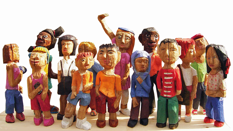 Zu sehen sind viele Kinder aus unterschiedlichen Ländern. Sie wurden aus Holz geschnitzt.