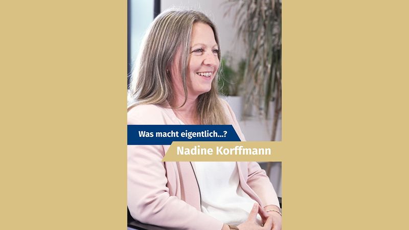 Zu sehen ist eine Frau. Sie tr&auml;gt einen rosafarbenen Blazer und sitzt auf einem Stuhl. Sie schaut nach rechts. Mittig steht auf einer blauen und einer gelben Farbfl&auml;che: "Was macht eigentlich...? Nadine Korffmann