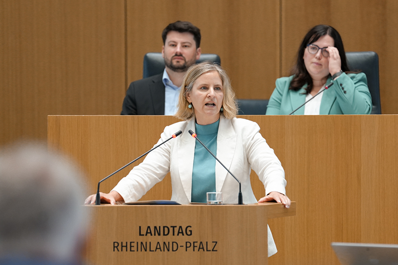 Eine Frau spricht in zwei Mikrofone am Redpult des Plenarsaals.