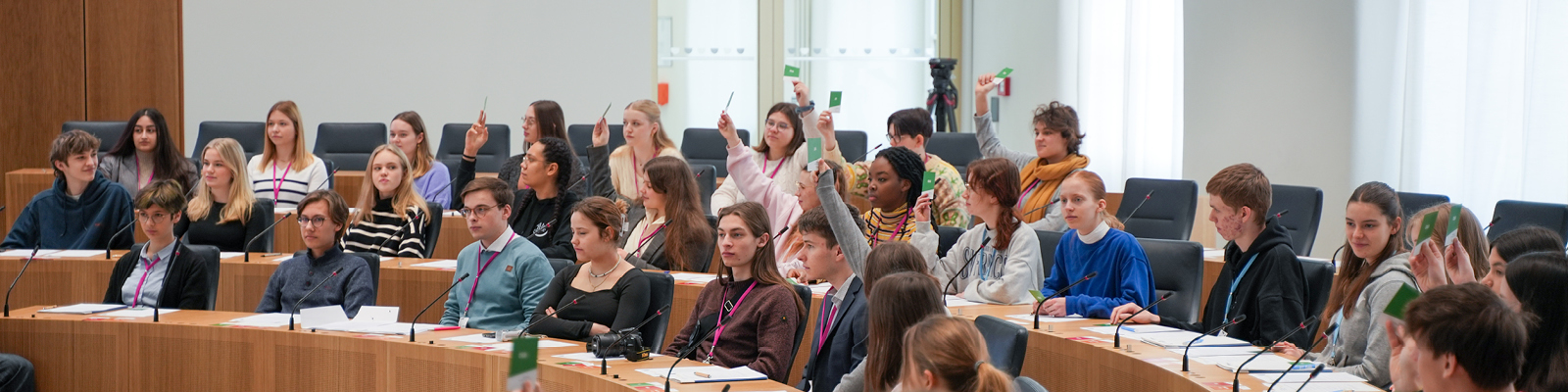 Zu sehen sind mehrere Schüler. Sie sitzen im Plenarsaal und hören gespannt zu.