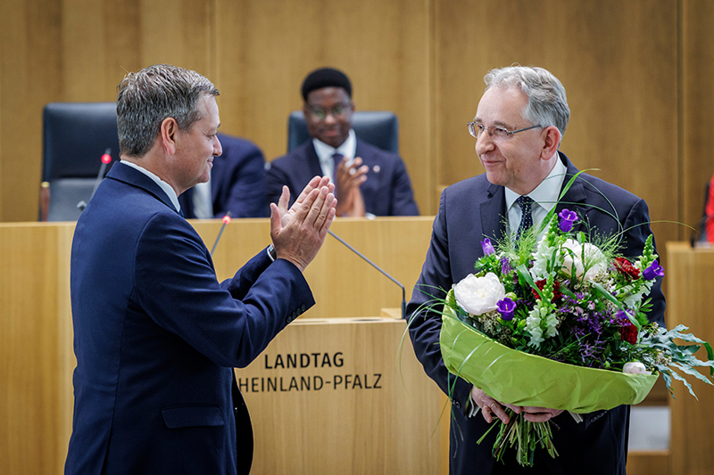 Herr Lammert steht mit einem großen Blumenstrauß im Plenarsaal. Vor ihm steht Christian Baldauf, der ihm applaudiert.