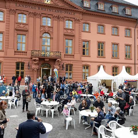 Viele Gäste sitzen im Hof vor dem Deutschhaus und hören der Eröffnungsrede von Hendrik Hering zu.