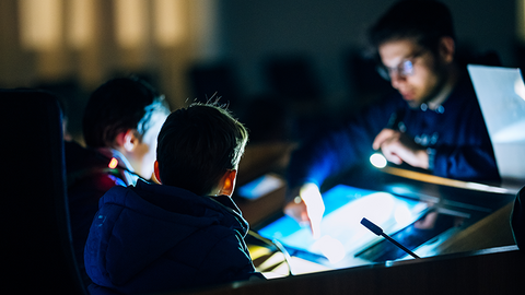 Zu sehen ist das Pult des Präsidenten im Plenarsaal im Dunkeln. Vor dem beleuchteten Pult stehen drei Kinder.
