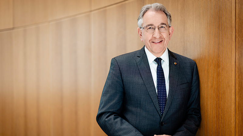 Matthias Lammert is standing in a meeting room in front of a wood-panelled wall