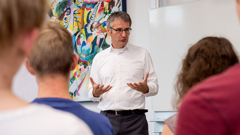 Landtagspräsident Hendrik Hering spricht vor einer Schulklasse. 