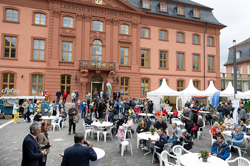 Viele Gäste sitzen im Hof vor dem Deutschhaus und hören der Eröffnungsrede von Hendrik Hering zu.